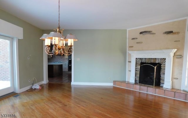 unfurnished living room with a fireplace, hardwood / wood-style floors, and a notable chandelier