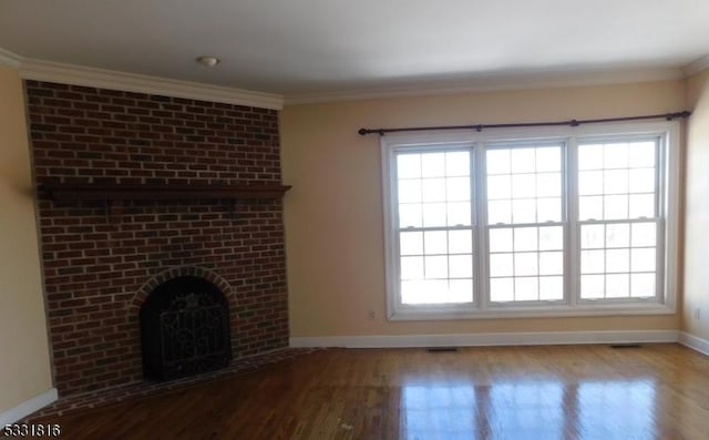 unfurnished living room with a brick fireplace, ornamental molding, a healthy amount of sunlight, and wood-type flooring