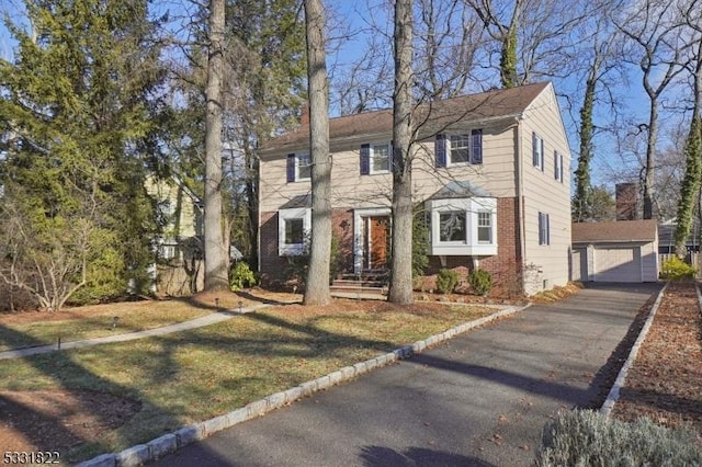 view of front of property featuring a front lawn, a garage, and an outdoor structure