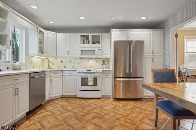 kitchen with stainless steel appliances, white cabinets, decorative backsplash, and sink