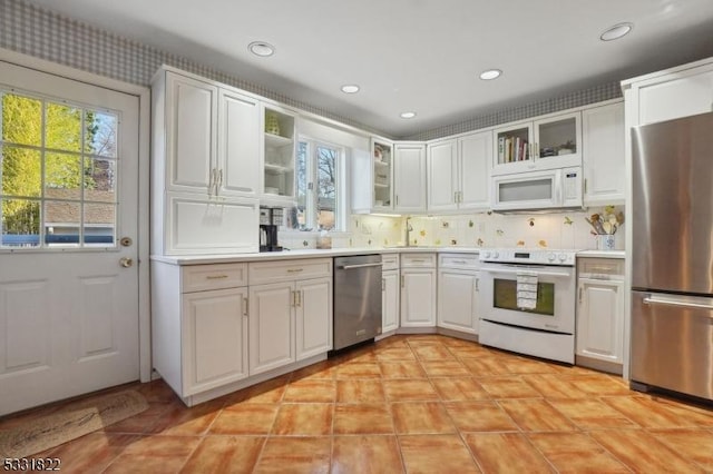 kitchen with sink, appliances with stainless steel finishes, tasteful backsplash, and white cabinetry