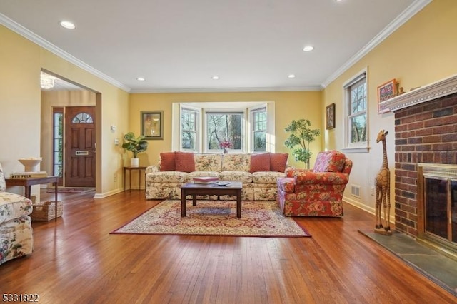 living room featuring a brick fireplace, crown molding, and hardwood / wood-style flooring