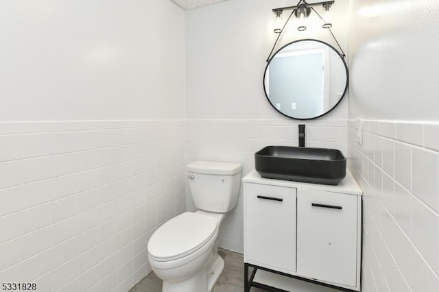 bathroom featuring vanity, tile walls, and toilet