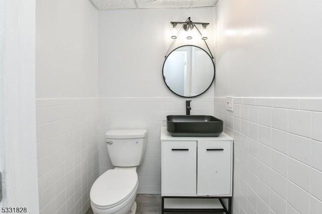 bathroom with vanity, tile walls, and toilet