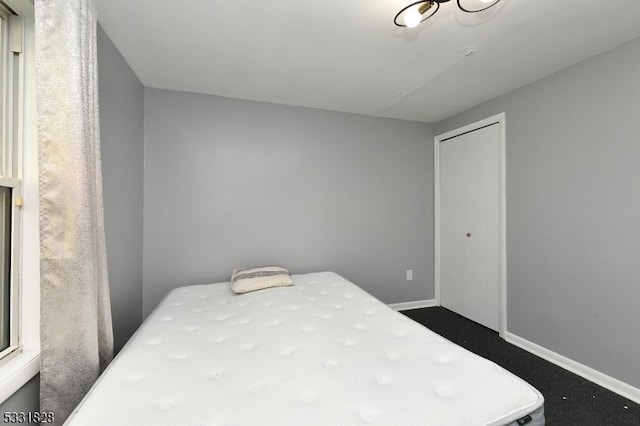 bedroom with dark colored carpet and a closet