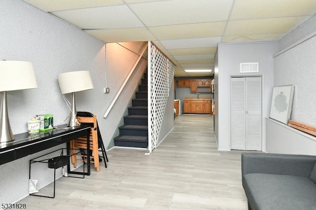 stairway with a paneled ceiling and wood-type flooring