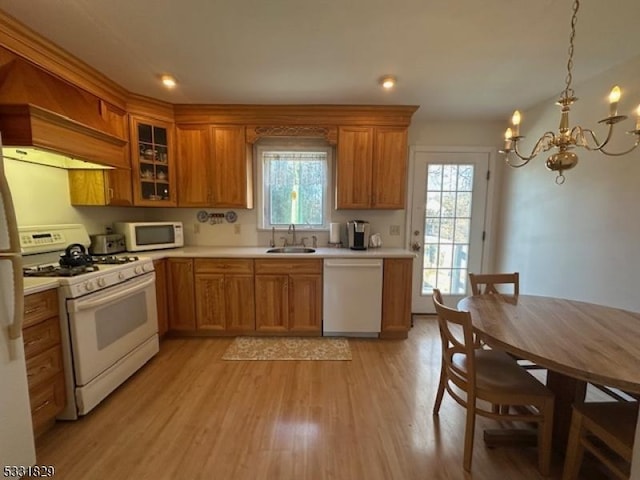 kitchen featuring white appliances, an inviting chandelier, sink, plenty of natural light, and light hardwood / wood-style floors