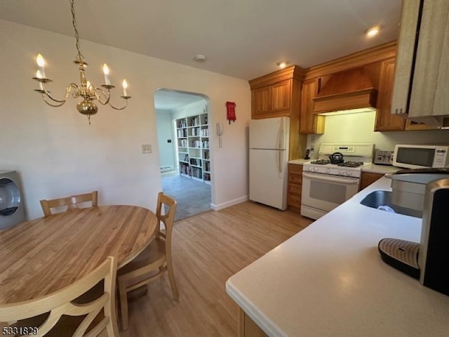 kitchen with a chandelier, decorative light fixtures, white appliances, light hardwood / wood-style floors, and custom range hood