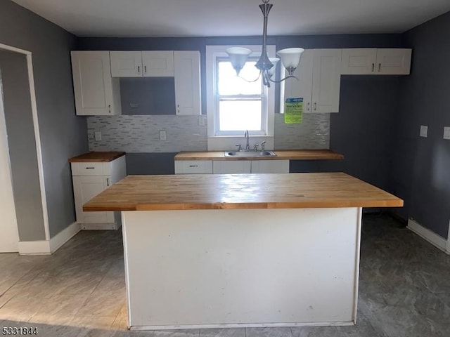 kitchen featuring pendant lighting, butcher block counters, a kitchen island, and white cabinetry