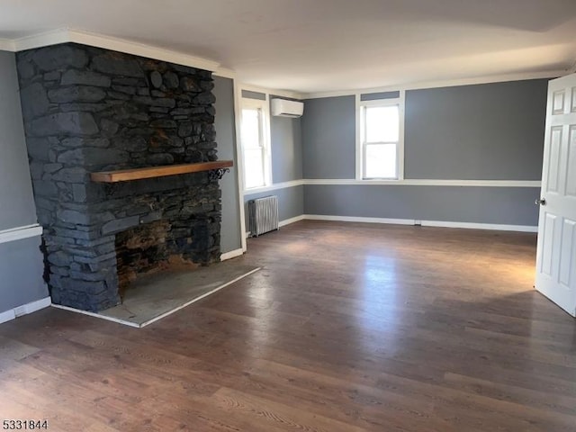 unfurnished living room with crown molding, an AC wall unit, radiator heating unit, dark hardwood / wood-style floors, and a stone fireplace