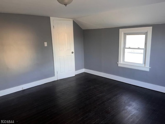 additional living space with dark wood-type flooring and vaulted ceiling