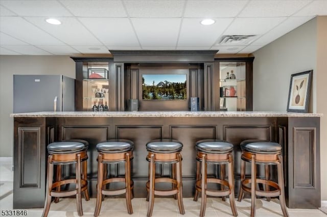 bar with a paneled ceiling and stainless steel refrigerator