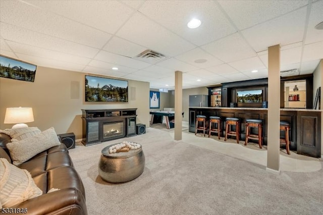 living room with light carpet, a fireplace, and a drop ceiling