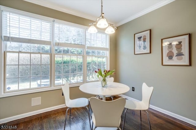 dining space featuring dark wood-type flooring, ornamental molding, and an inviting chandelier