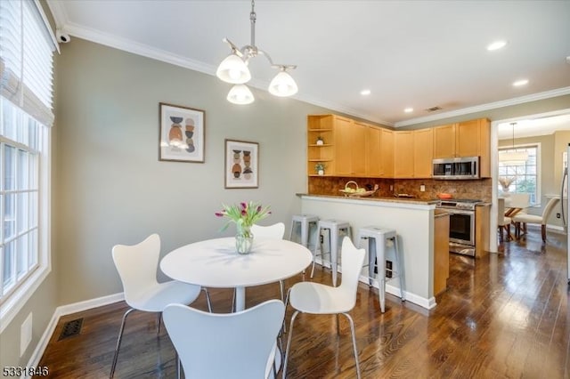 dining room with dark hardwood / wood-style flooring and crown molding