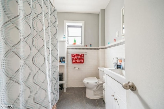 bathroom with a shower with shower curtain, tile patterned floors, vanity, tile walls, and toilet