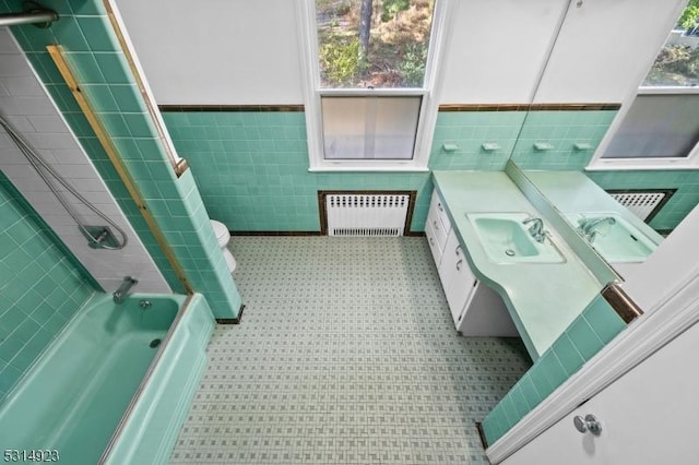 full bathroom with shower / washtub combination, toilet, vanity, radiator, and tile walls