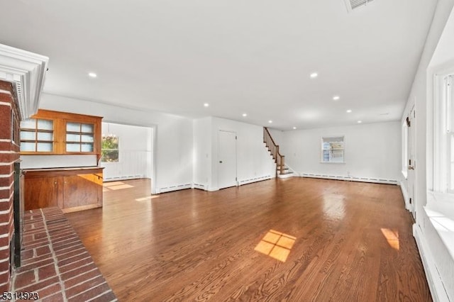 unfurnished living room featuring wood-type flooring and a baseboard heating unit