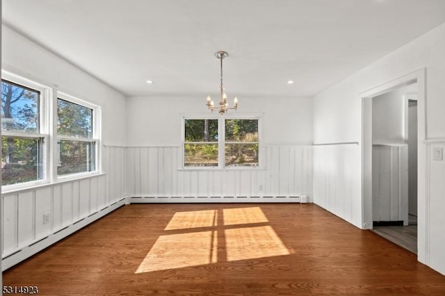 unfurnished dining area with wood-type flooring, a baseboard radiator, an inviting chandelier, and plenty of natural light