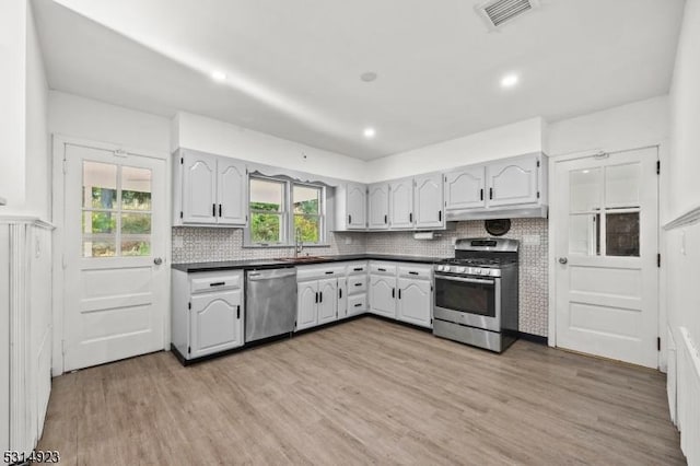 kitchen featuring appliances with stainless steel finishes, light hardwood / wood-style flooring, backsplash, and sink