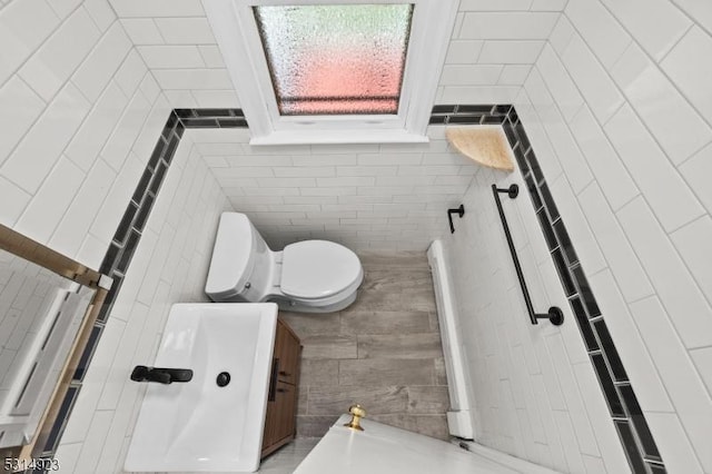 bathroom featuring toilet and tile walls