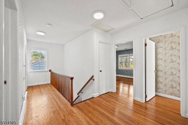 corridor featuring a baseboard heating unit and hardwood / wood-style flooring