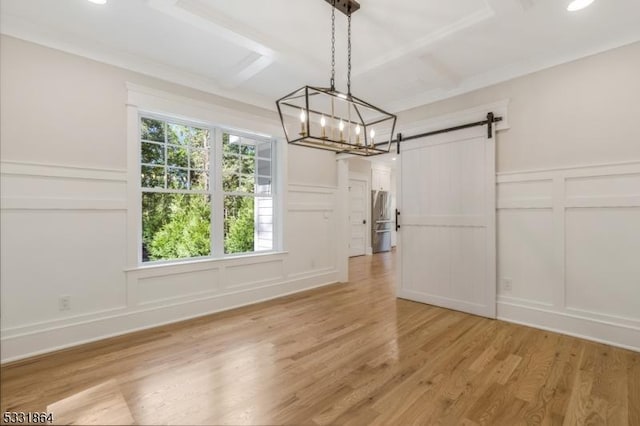 unfurnished dining area with coffered ceiling, a chandelier, a barn door, and light hardwood / wood-style flooring