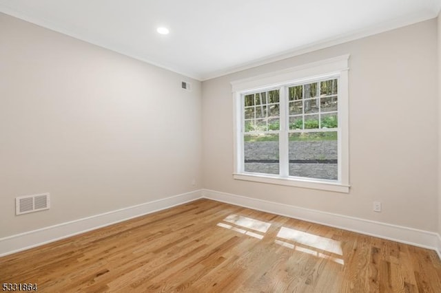 empty room featuring ornamental molding and hardwood / wood-style floors