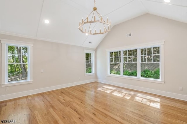 unfurnished room featuring lofted ceiling, a notable chandelier, and hardwood / wood-style floors