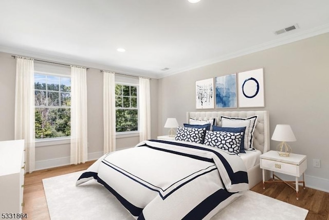 bedroom with crown molding and light hardwood / wood-style flooring