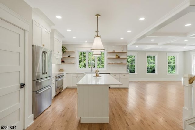 kitchen with appliances with stainless steel finishes, a kitchen island, white cabinetry, beamed ceiling, and hanging light fixtures