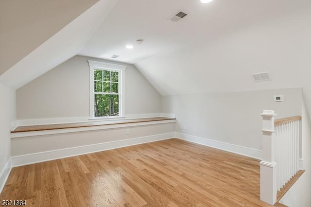 additional living space featuring light hardwood / wood-style floors and vaulted ceiling