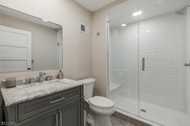 bathroom featuring toilet, vanity, an enclosed shower, and tile patterned floors