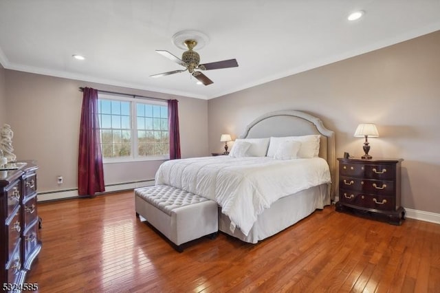 bedroom featuring hardwood / wood-style floors, a baseboard heating unit, ceiling fan, and crown molding