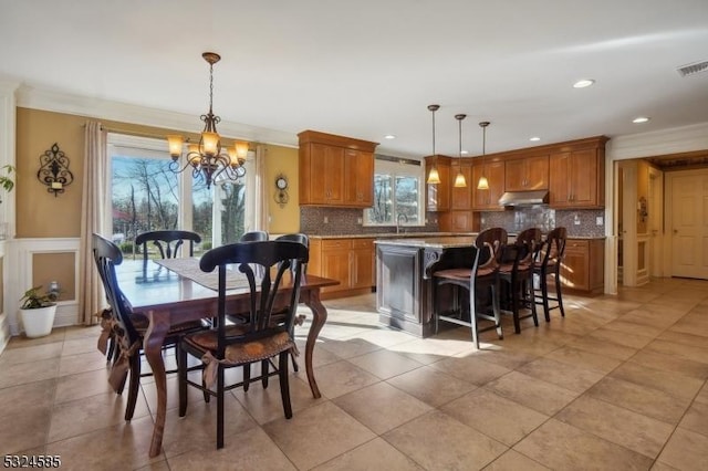 dining area featuring sink, light tile patterned flooring, ornamental molding, and an inviting chandelier