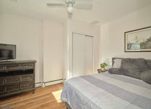 bedroom featuring a ceiling fan, a closet, light wood finished floors, and a baseboard radiator