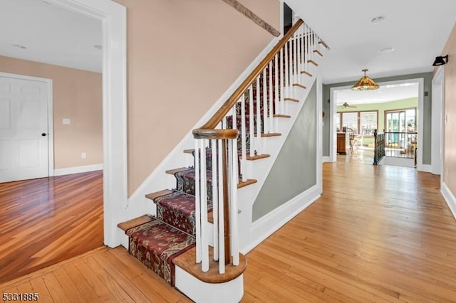 stairs with ceiling fan and hardwood / wood-style flooring