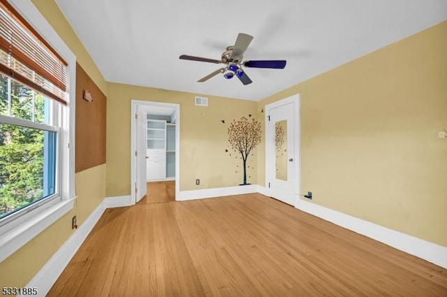 spare room featuring light hardwood / wood-style floors, ceiling fan, and a healthy amount of sunlight