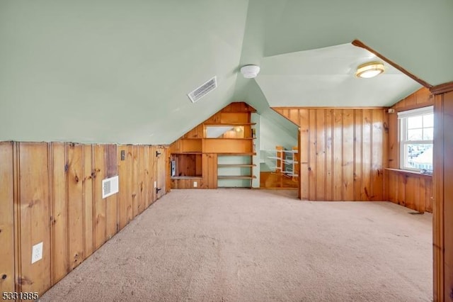 additional living space with carpet floors, vaulted ceiling, and wood walls