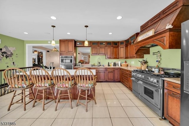 kitchen featuring a breakfast bar, sink, decorative light fixtures, light tile patterned flooring, and stainless steel appliances