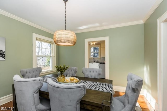 dining space with sink, hardwood / wood-style floors, and ornamental molding