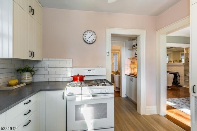 kitchen featuring light hardwood / wood-style floors, white cabinetry, white range with gas stovetop, and tasteful backsplash