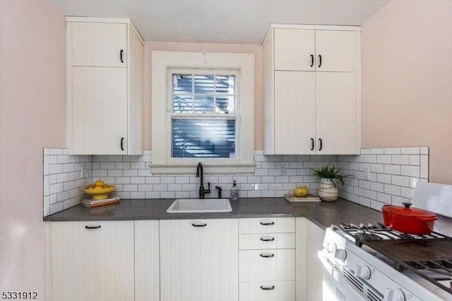 kitchen featuring backsplash, white cabinets, white range with gas cooktop, and sink