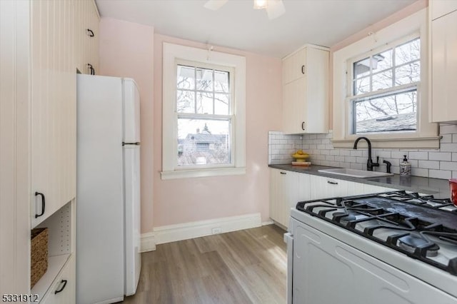 kitchen featuring white appliances, tasteful backsplash, white cabinetry, and sink