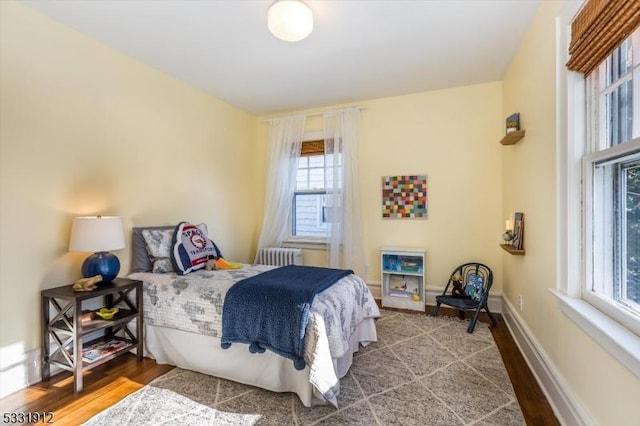 bedroom featuring radiator heating unit and hardwood / wood-style floors