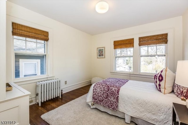 bedroom with dark wood-type flooring, radiator heating unit, and multiple windows