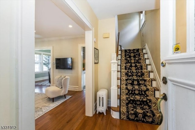 stairway featuring radiator heating unit, hardwood / wood-style floors, and crown molding