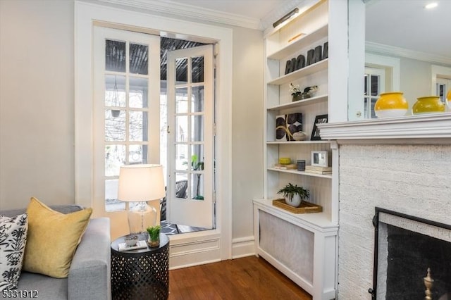 doorway to outside featuring a stone fireplace, crown molding, and dark wood-type flooring