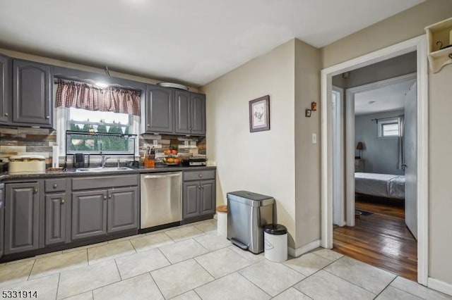 kitchen featuring gray cabinets, sink, dishwasher, and tasteful backsplash