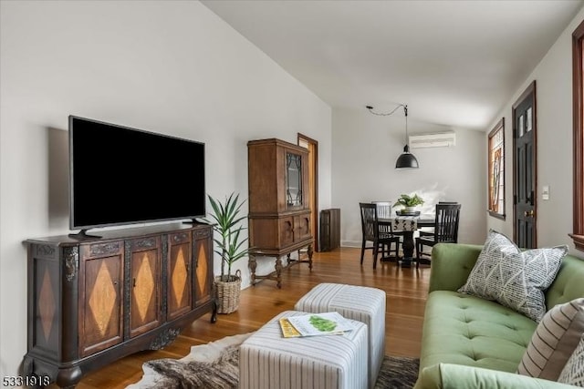 living room with hardwood / wood-style floors, a wall unit AC, and vaulted ceiling